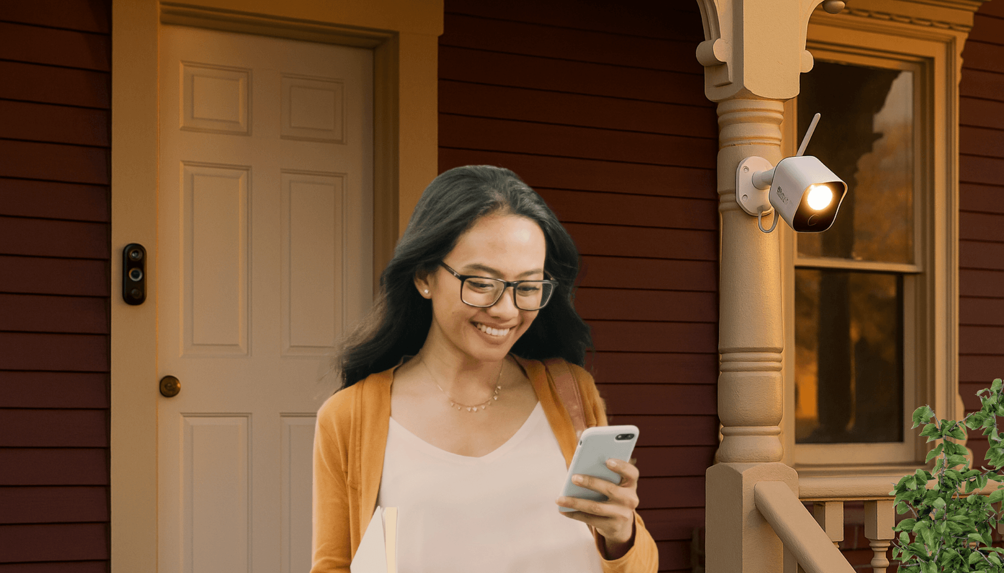 Smart Security Cameras for Safer Homes - One Entry at a Time | woman looking at her phone and walking down the front steps of the burgundy victorian house with the doorbell v3 near the white front door and the floodlight camera by the porch near a plant