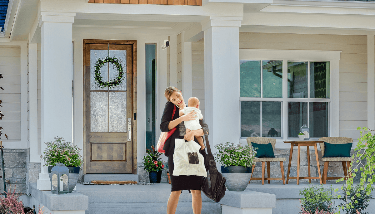 Person carrying a baby and bags beside a front door with a Toucan S4 camera