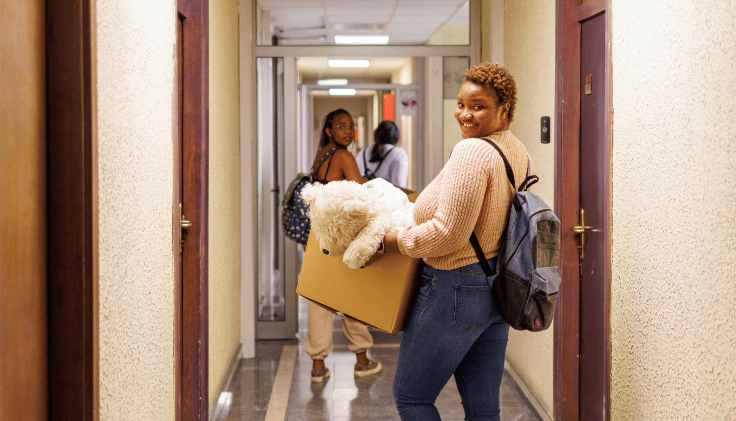 Smart Cameras for College Safety - A Parent’s Guide | college girls walking in a dorm hallway with boxes and bags with the toucan solutions wireless video doorbell v3 installed near one of the doors