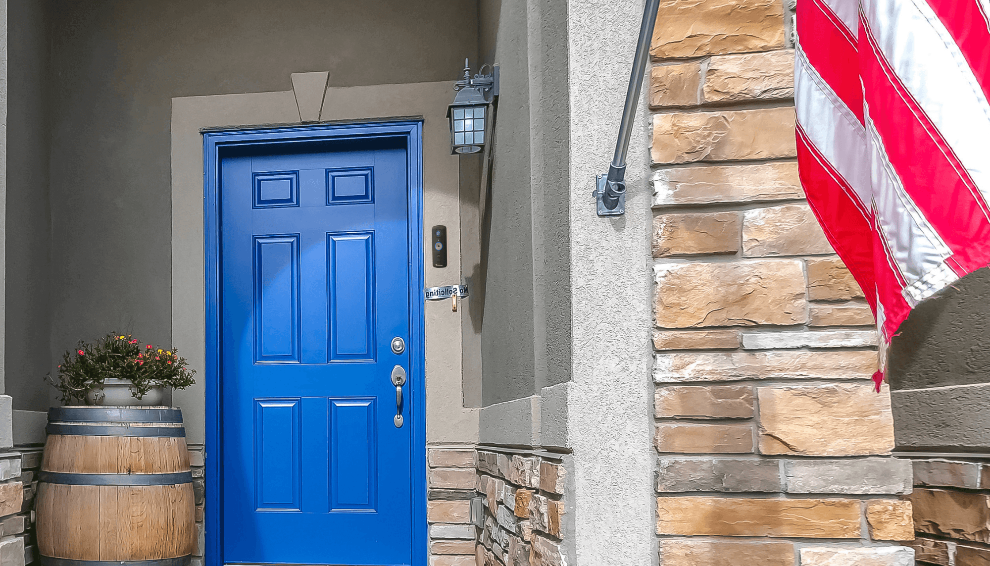 Secure Your July 4 Bash with Wireless Home Security Cameras | Wireless Home Security Cameras - home with blue front door and a doorbell v3 installed beside it and an american flag by the porch