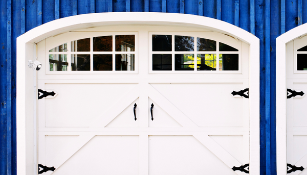 The Toucan Solutions floodlight camera installed near the two door entrance of a blue barn