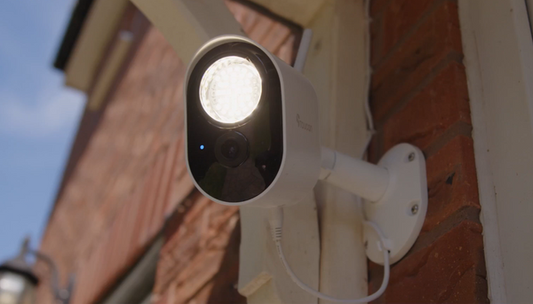 Toucan Solutions' Security Floodlight Camera installed on the side of a house with the LED lights on during early evening