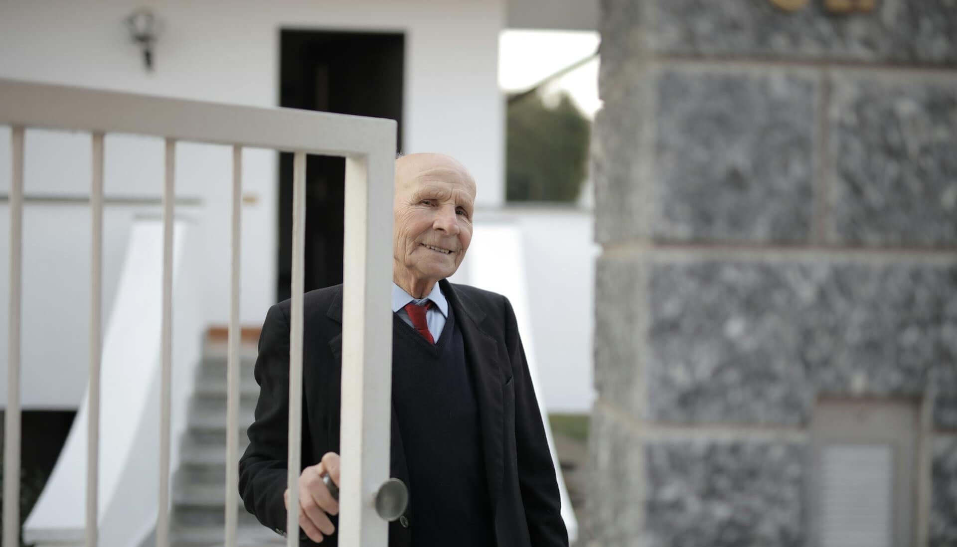 10 Smart Security Tips for Caregivers to Keep Loved Ones Safe | Senior Man in Black Suit Standing Opening The Door