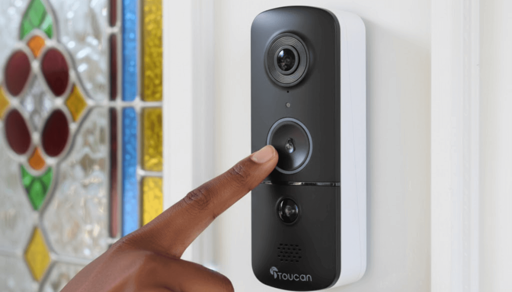 Why DIY Home Security Fits Busy Family Life | DIY Home Security - person of color's hand ringing the Toucan Solutions wireless video doorbell camera v3 installed on a white house with a colorful stained glass door