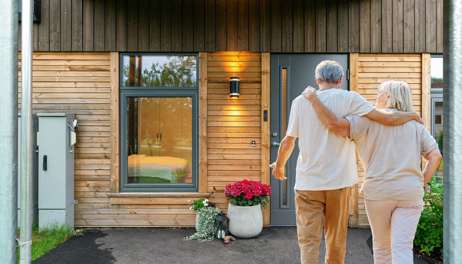 elderly couple walking to the front of their house with gray door and the wireless doorbell camera v3 installed beside it