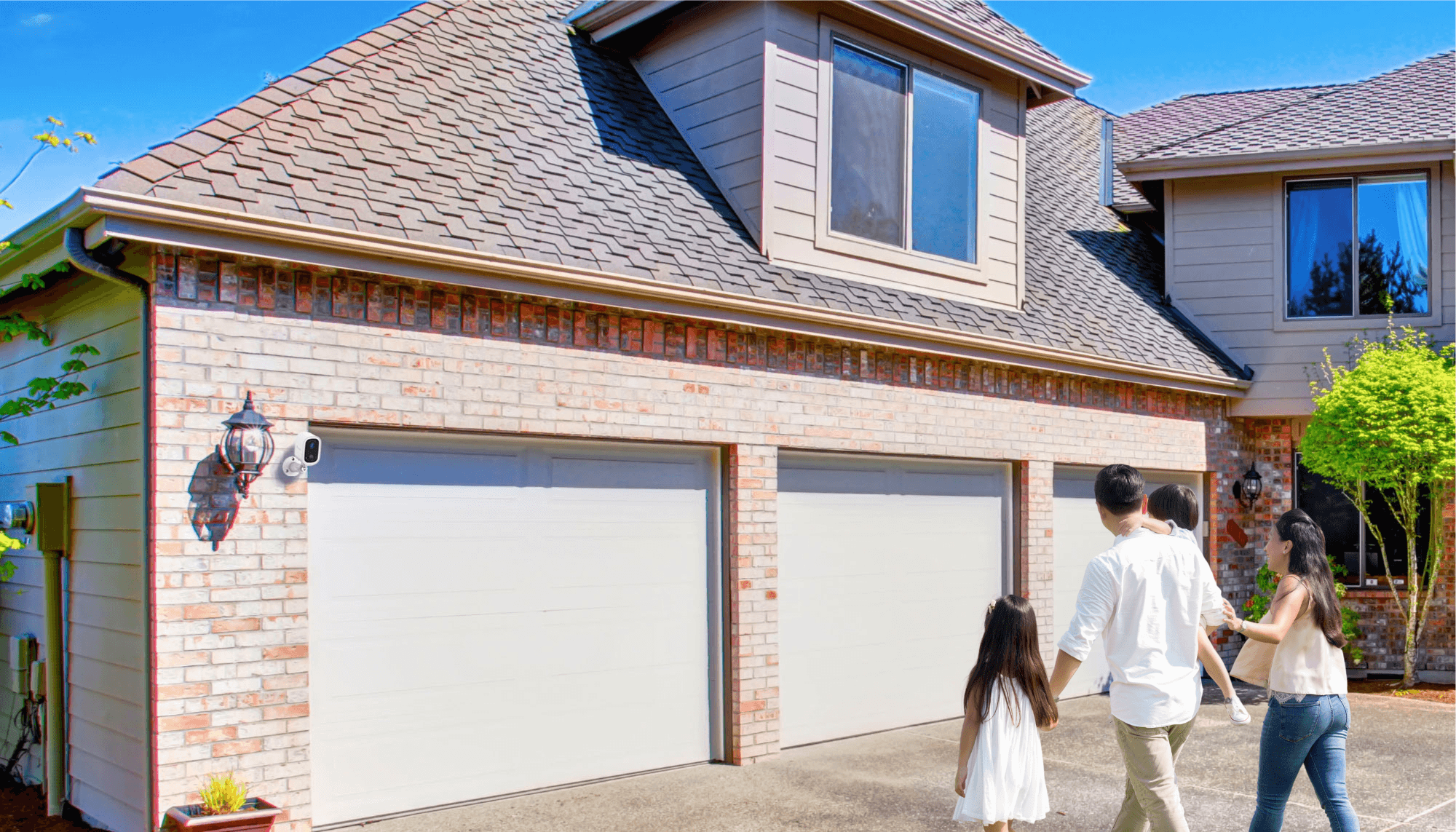 10 Tips to Keep Summer Staycations Safer With Smart Cameras | family of four walking toward their home's driveway and garage with the Toucan Solutions Wireless Security Camera S4 installed beside the sconce