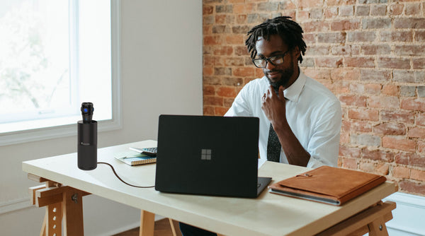 small business owner sitting in front of laptop with the Toucan Video Conference System 360 on the table