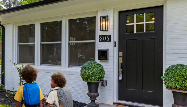 two young school kids walking away from their home's front door with a toucan wireless video doorbell camera v3 installed beside it