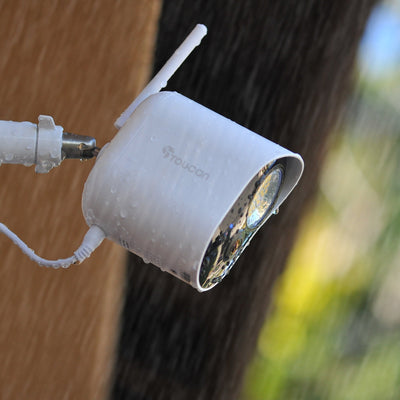 Toucan Security Floodlight Camera with water droplets showcasing its outdoor durability and high-tech features.